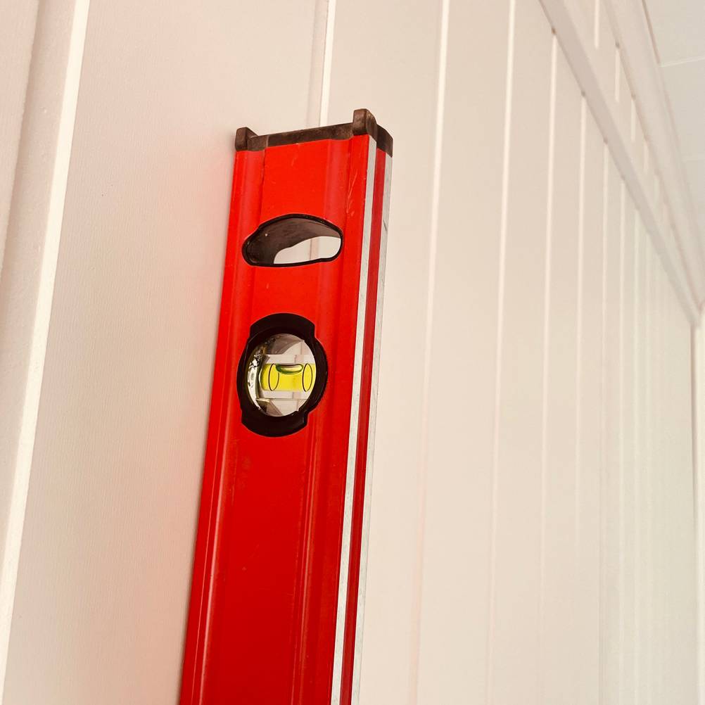 Rote Wasserwaage vertikal an der Wand angelegt.