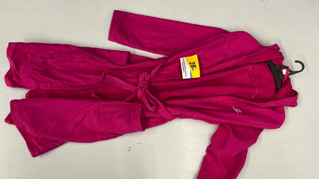 Rosa getesteter Bademantel für Damen liegt inklusive Preisschild und Bügel ausgebreitet auf hellem Boden.
