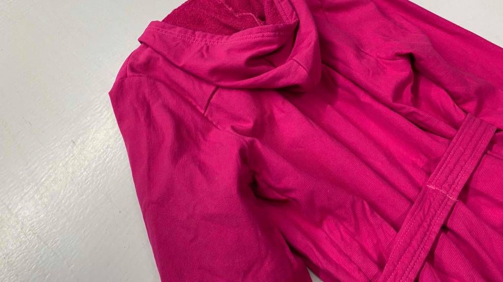 Nahaufnahme von einem rosa Damen-Bademantel im Test mit Blick auf den Gürtel und die Kapuze.