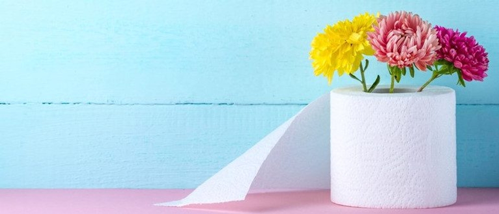 Toilettenrolle mit Blumen vor einer blauen Wand.