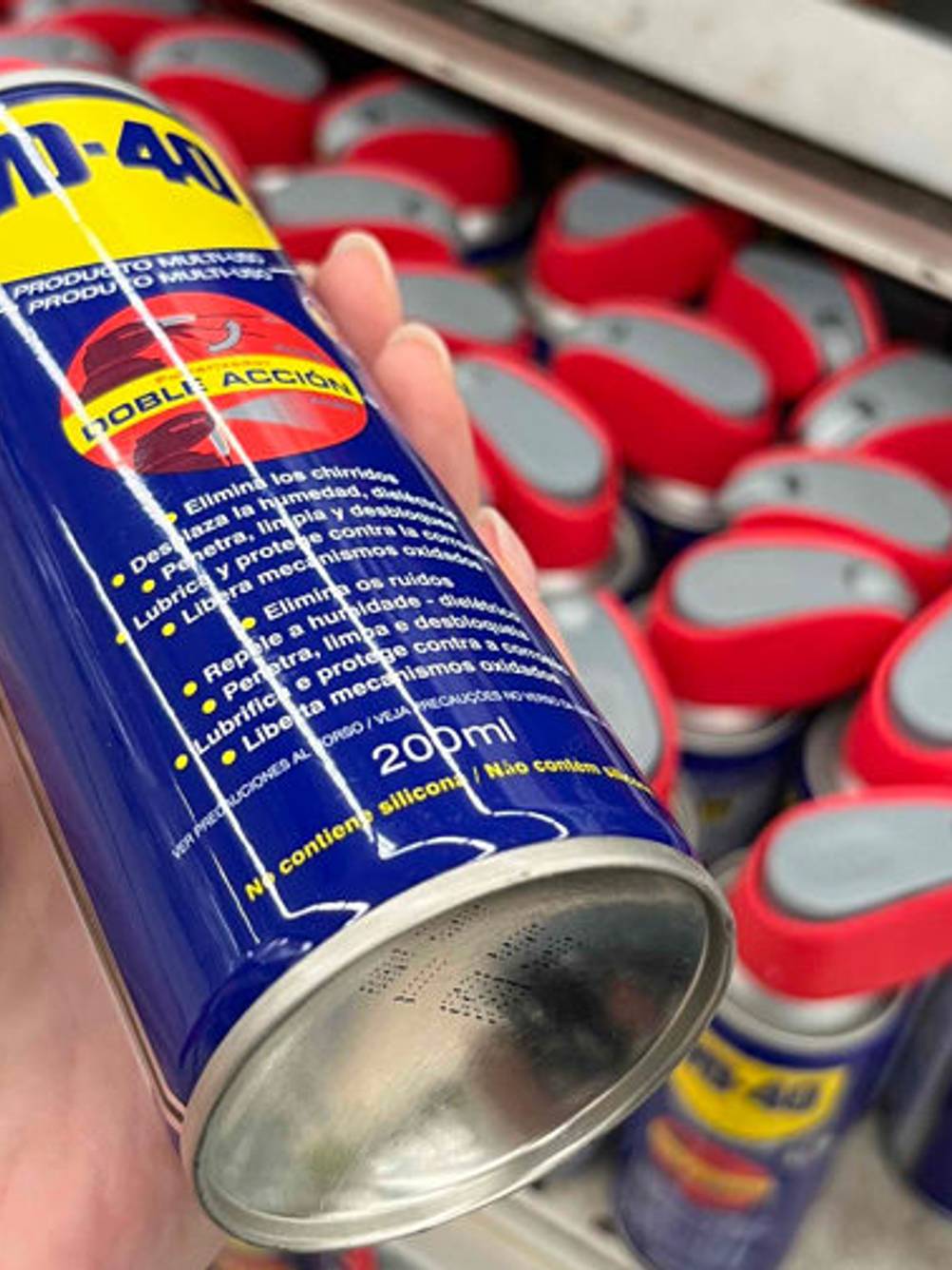 Hand hält ein getestetes Druckluftspray von WD 40, mit Blick auf den Dosenboden, vor einem Verkaufsregal.