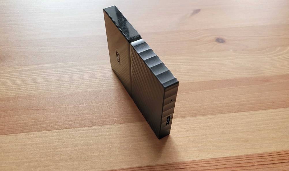 Eine getestete externe SSD Festplatte mit 1 TB steht auf einer Holzfläche, Blick von oben.