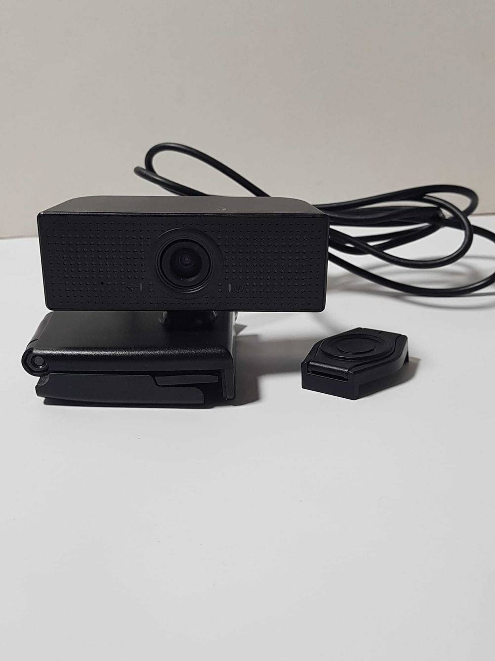 Eine Webcam mit Mikrofon im Test mit Halterung und Kabel auf einer hellen Fläche.