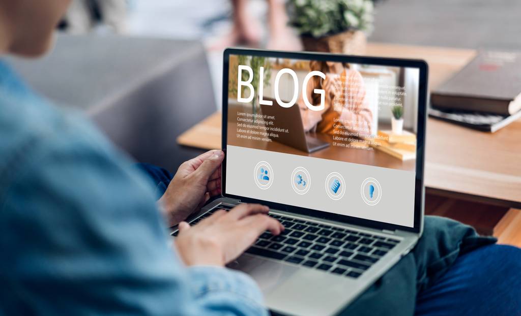 Eine Person verwendet einen Laptop, auf dem gerade ein Blog geöffnet wird.