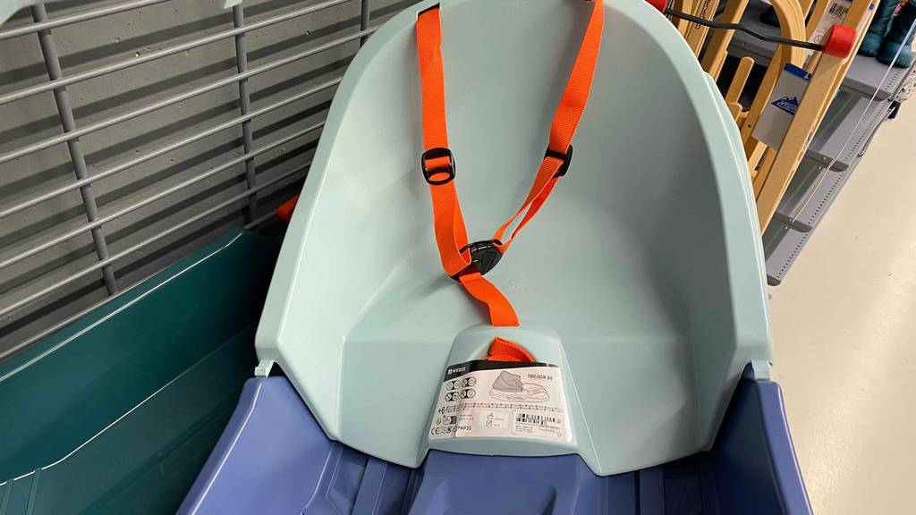 Detailaufnahme des orangen Haltegurts eines Babyschlittens der zum Test bereitsteht und sich in einem Verkaufsbereich für Schlitten befindet.