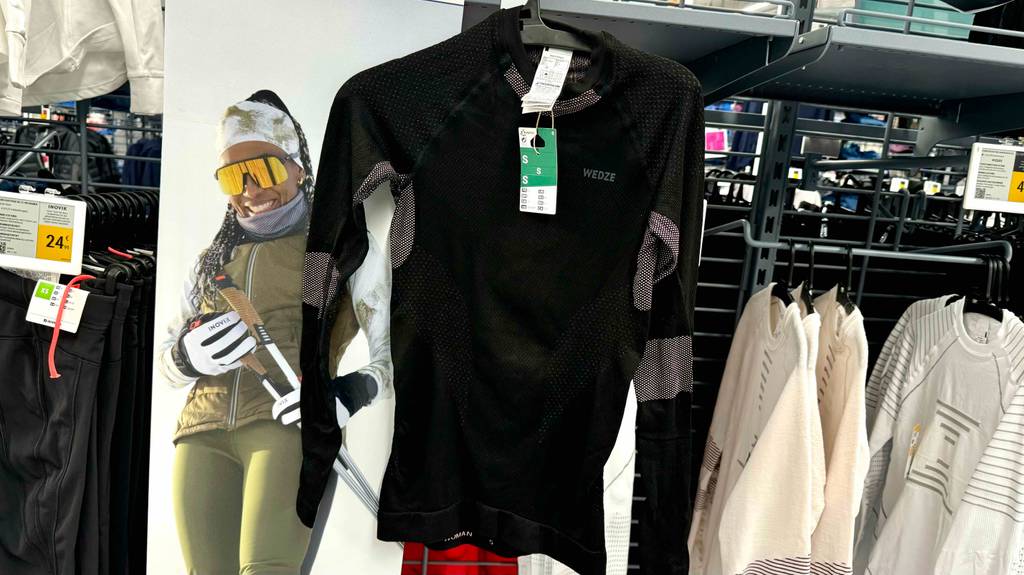 Das Oberteil von Ski-Unterwäsche für Damen hängt zum Testen in einem Regal zwischen anderen Produkten.