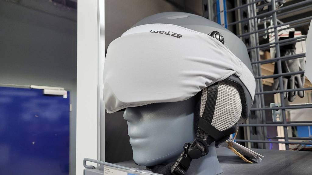 Ansicht des mit Schutzhaube gesicherten Visiers von einem grauen Skihelm mit Visier im Test, der sich in einem Verkaufsregal auf einem Puppenkopf befindet.