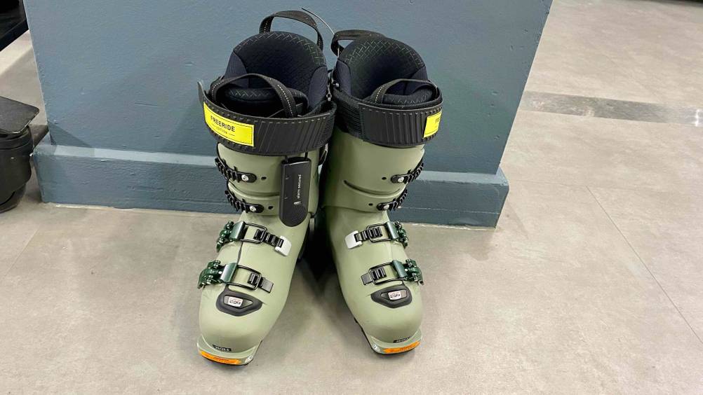 Vor einer blauen Wand steht ein Paar Skischuhe im Test von vorne.