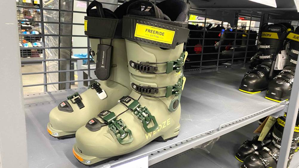 Ein Paar getestete Skischuhe von schräg vorne neben anderen im Verkaufsregal.
