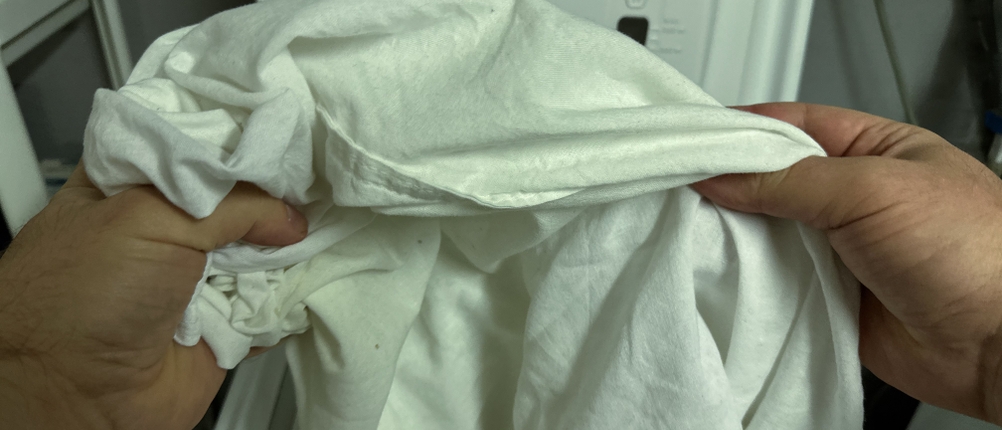 Bettwäsche wird in die Waschmaschine gefüllt.