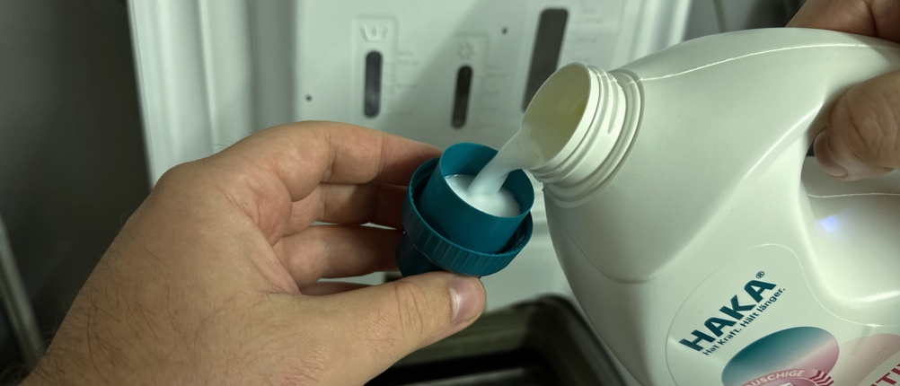 Etwas Weichspüler von HAKA wird in die Dosierkappe gefüllt.