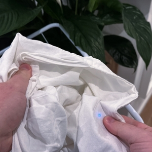 Ein getrockneter Kopfkissenbezug wird durch zwei Hände hochgehalten.