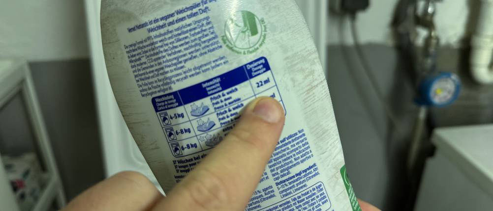 Ein Finger zeigt auf Informationen der Rückseite des veganen Weichspülers von Vernel.