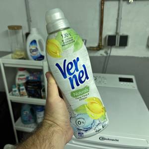 Eine Hand hält die Flasche des veganen Weichspülers von Vernel hoch.