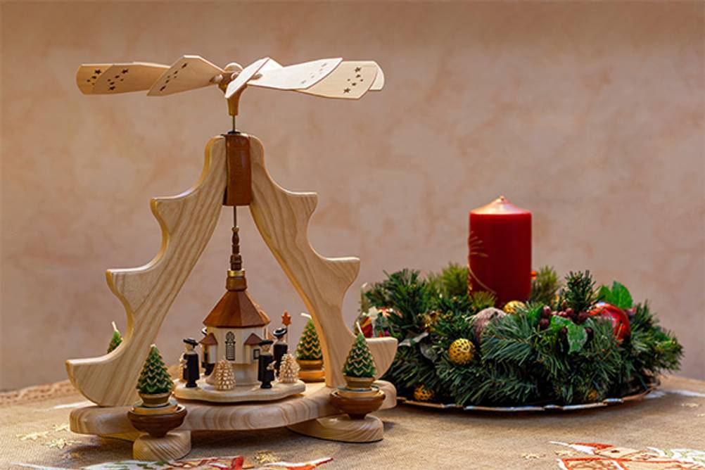 Weihnachtspyramide im Test: Eine moderne Variante der Weihnachtspyramide mit Kerzen in Tannenform neben einem Adventskranz.