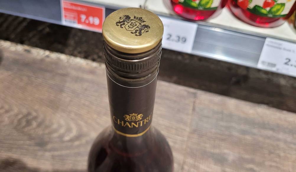 Nahaufnahme des Schraubverschlusses einer Flasche des getesteten Weinbrands vor einem Regal.