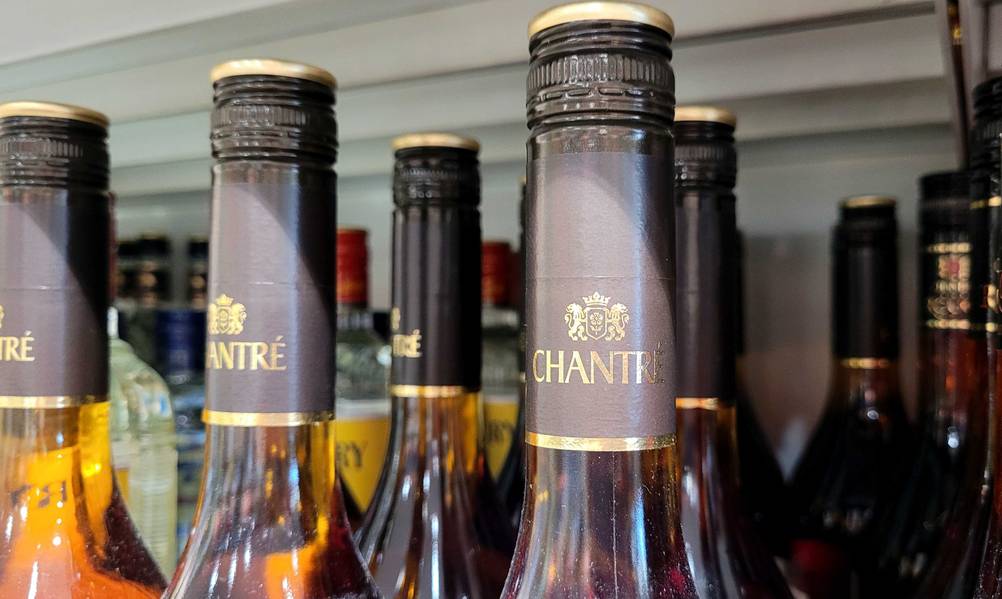 Nahaufnahme des Flaschenhalses des Weinbrands im Test mit Logo neben anderen Flaschen.