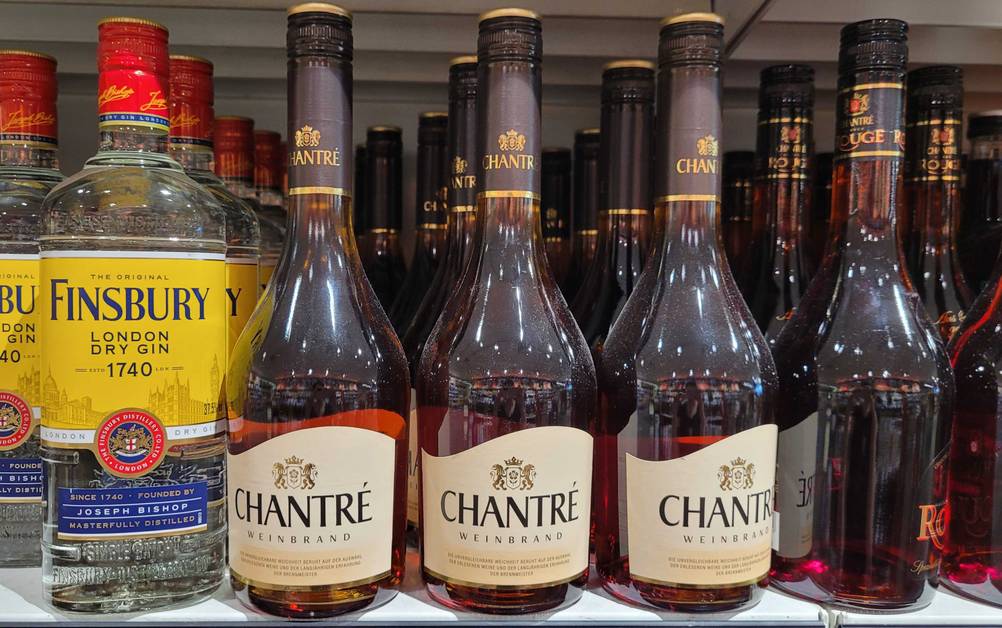 Weinbrand im Test: Mehrere Flaschen stehen neben anderen Produkten im Regal.