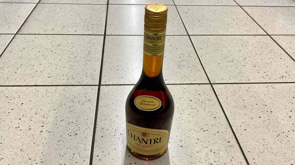 Auf dem Boden steht eine Flasche getesteter Weinbrand.