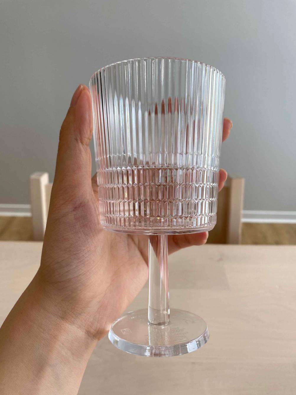 Eine Hand hält ein getestetes Weinglase über einen Tisch.