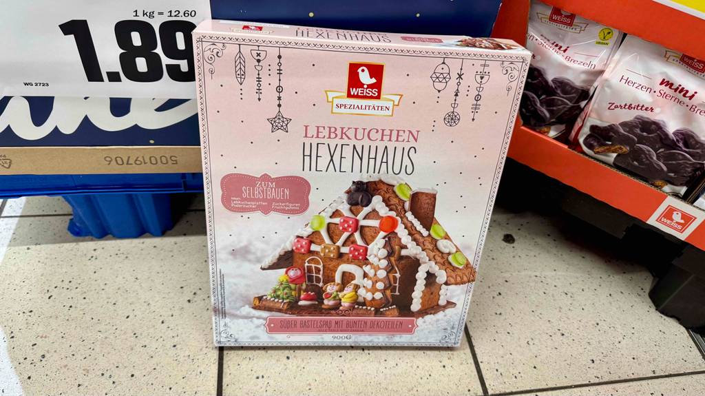 Das getesteteLebkuchenhaus zum Zusammenbauen, enthalten in einer 900-g-Schachtel, die vor einem Süßwarenregal im Supermarkt steht.