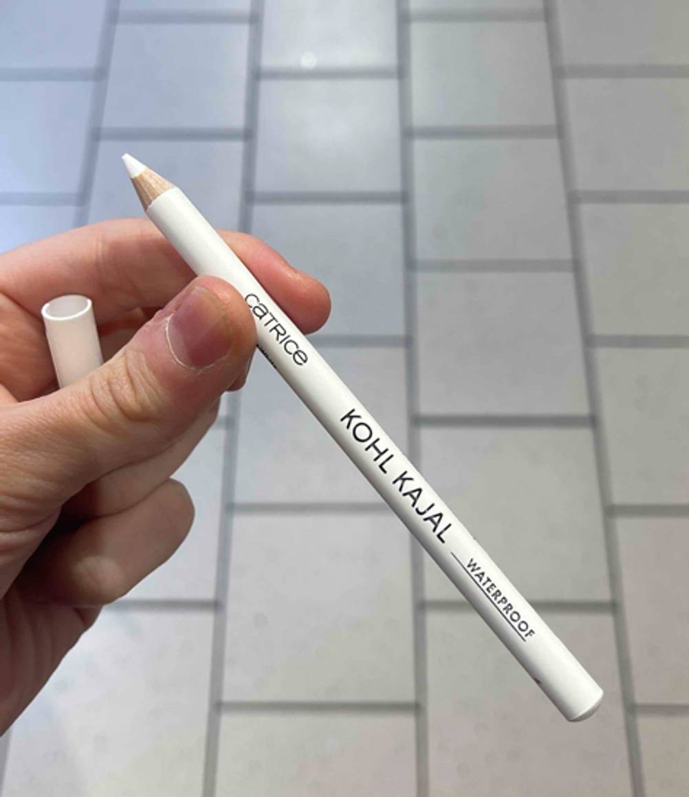 Eine Hand hält den weißen Kajal ohne Verschlusskappe.