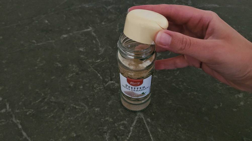 Geöffneter Kunststoffbehälter mit getestetem weißen Pfeffer.