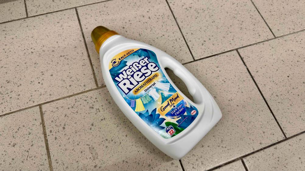 Eine Flasche des getesteten Weißer-Riese-Waschmittels auf einem Fließenboden liegend.