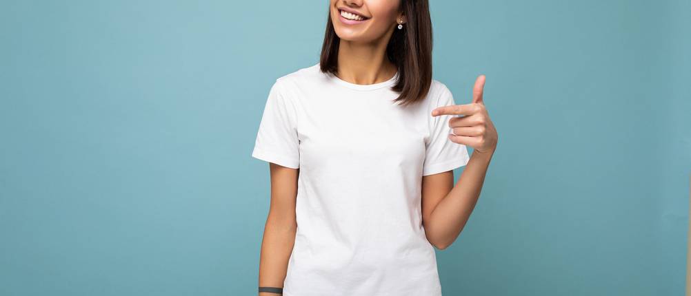 Weißes T-Shirt für Damen im Test: Frau trägt weißes T-Shirt und steht vor blauer Wand.