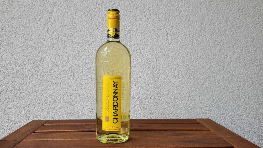 Eine Flasche Weißwein im Test auf einem Holztisch vor einer hellen Wand.