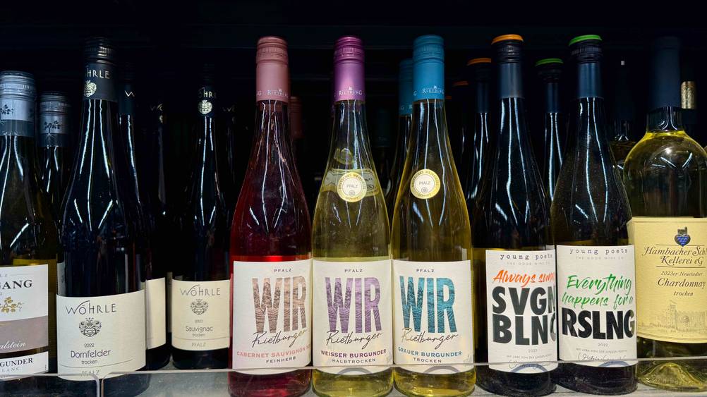 Mehrere Flaschen des getesteten Weißwein (halbtrocken) in einem Verkaufsregal neben anderen Sorten.