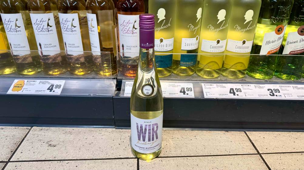 Weißwein (halbtrocken) getestet: Eine Flasche steht vor einem Verkaufsregal mit Preisangaben.