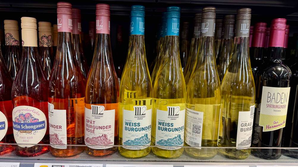 Mehrere Flaschen des getesteten Weißwein (trocken) in einem Verkaufsregal neben anderen Sorten.