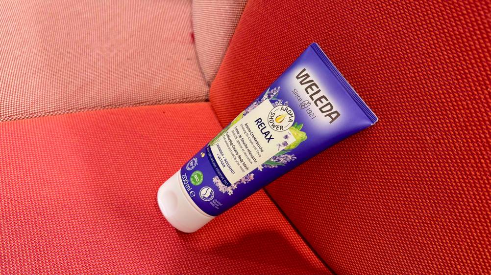Eine Tube des getesteten Weleda-Duschgels leicht seitlich auf einem roten Polster.