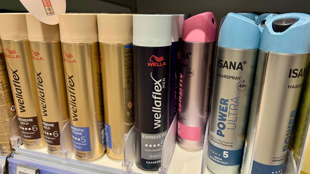 In einem Verkaufsregal stehen mehrere Dosen des Wella-Haarsprays im Test neben anderen Produkten.