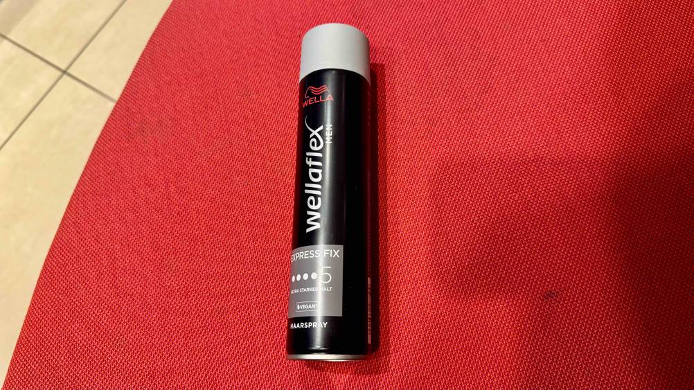 Eine Dose des getesteten Wella-Haarsprays von schräg oben auf einer roten Fläche.