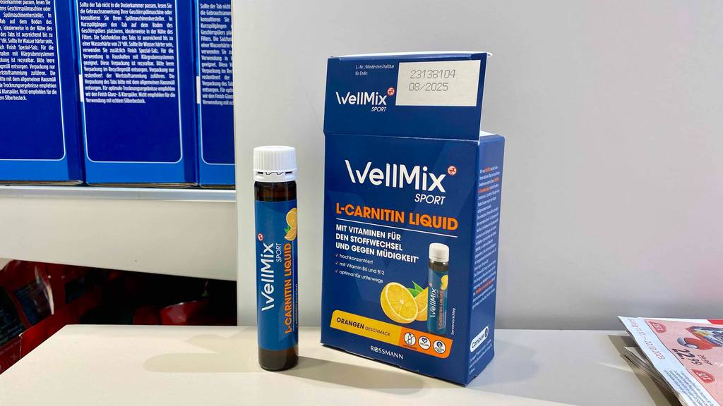 L-Carnitin im Test: Ein Behälter steht vor der Originalverpackung, auf der Infos zur Verwendung angegeben sind.