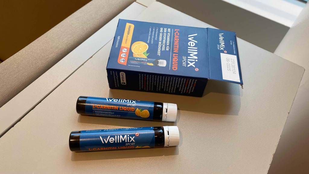 Zwei Fläschchen getestetes L-Carnitin liegen unterhalb des Verpackungskartons.