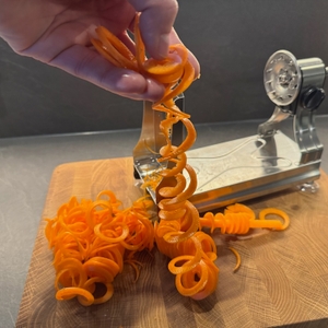 Eine Hand hebt Karottenspiralen in die Höhe.