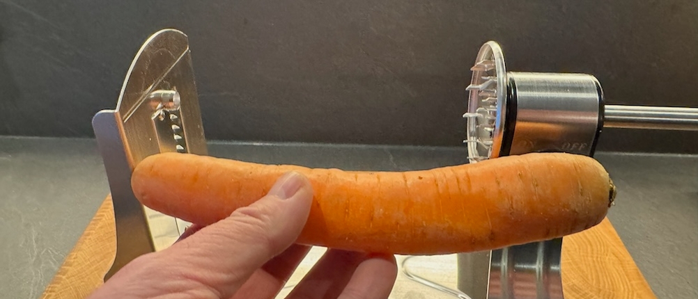 Nahansicht einer Karotte, die vor den Spiralschneider gehalten wird.