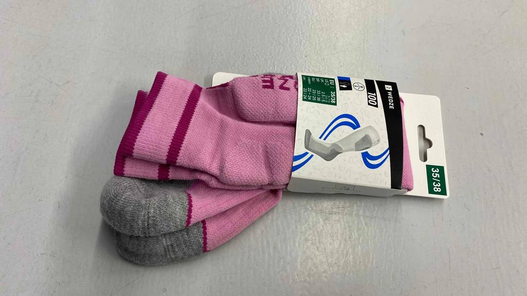 Rosa Wende-Skisocken im Test: mit grauer Sohlen-Verstärkung liegen sie in ihrer Verpackung auf einer hellen Oberfläche.