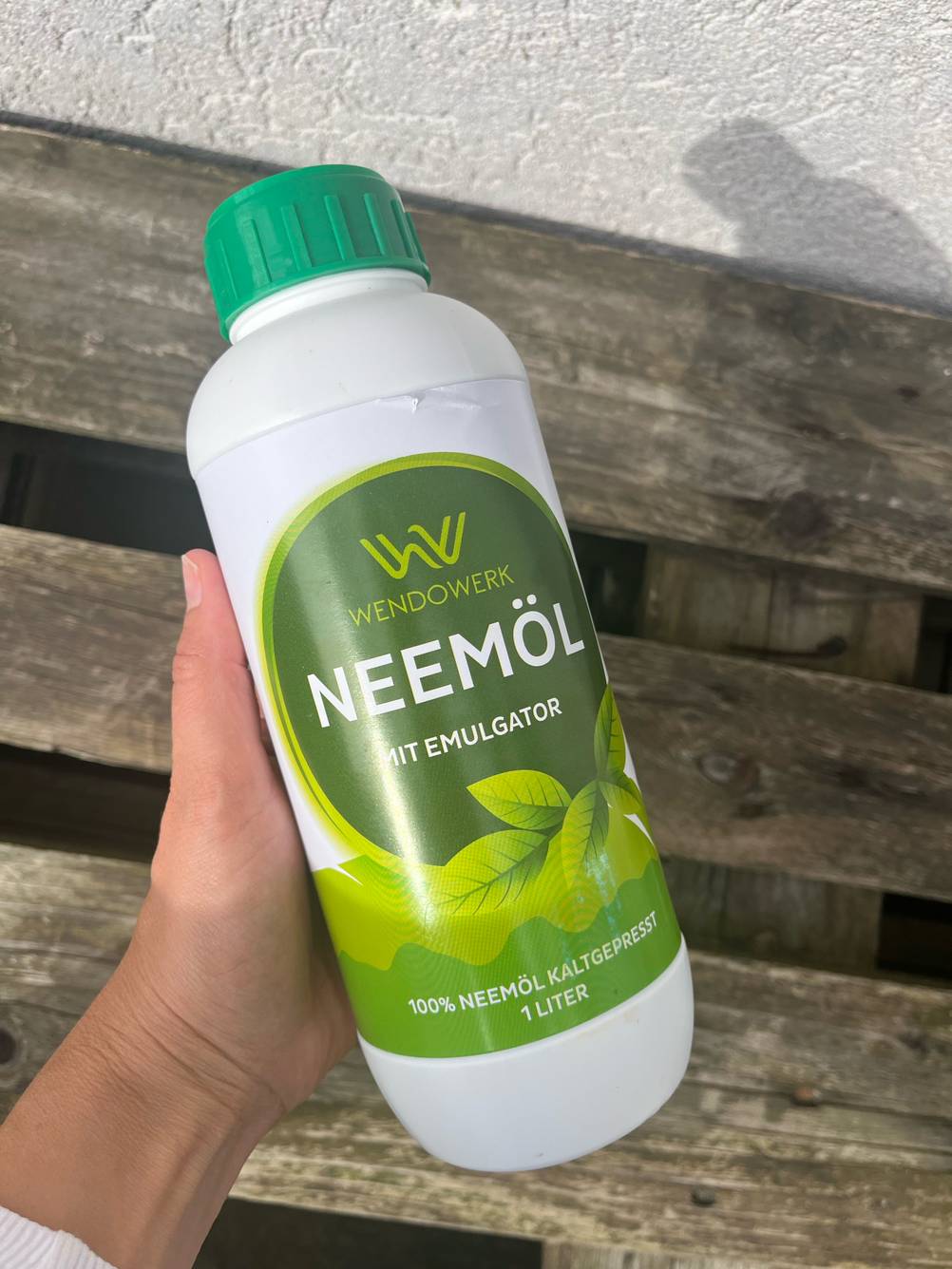 Eine Hand hält eine Flasche Neemöl zum Testen über einer Palette.