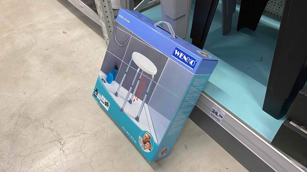Duschhocker getestet: Verpackung mit Duschhocker lehnt an Regal.