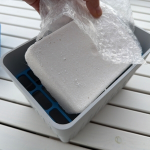 Ein Block Granulat aus dem Wenko-Nachfüllpack für Luftentfeuchter wird in einen Luftentfeuchter gelegt