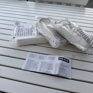 Drei Packungen Granulat aus dem Wenko-Nachfüllpack für Luftentfeuchter liegen neben der Anleitung auf einem Tisch