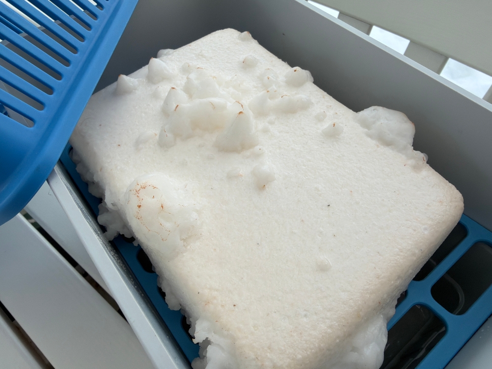 Ein Block Granulat aus dem Wenko-Nachfüllpack für Luftentfeuchter liegt leicht aufgelöst in einem Luftentfeuchter