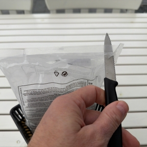 Eine Packung mit Granulat vom Wenko-Raumentfeuchter Cube WK50220 wird aufgeschnitten