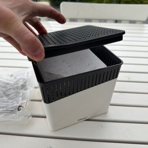 Eine Hand legt den Deckel auf den Wenko-Raumentfeuchter Cube WK50220