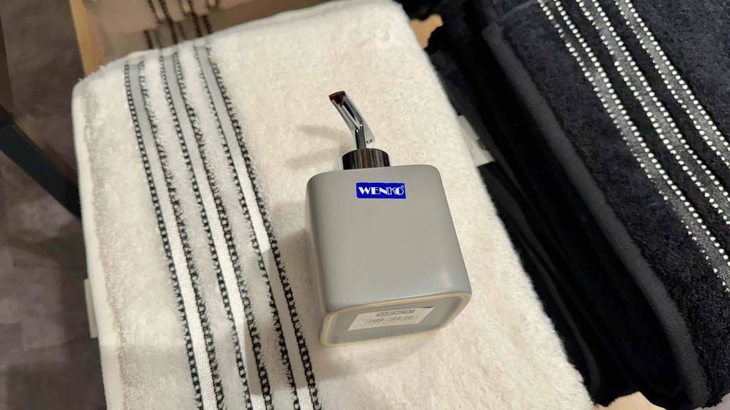 Ein Seifenspender in grau liegt zum testen auf einem Handtuch.