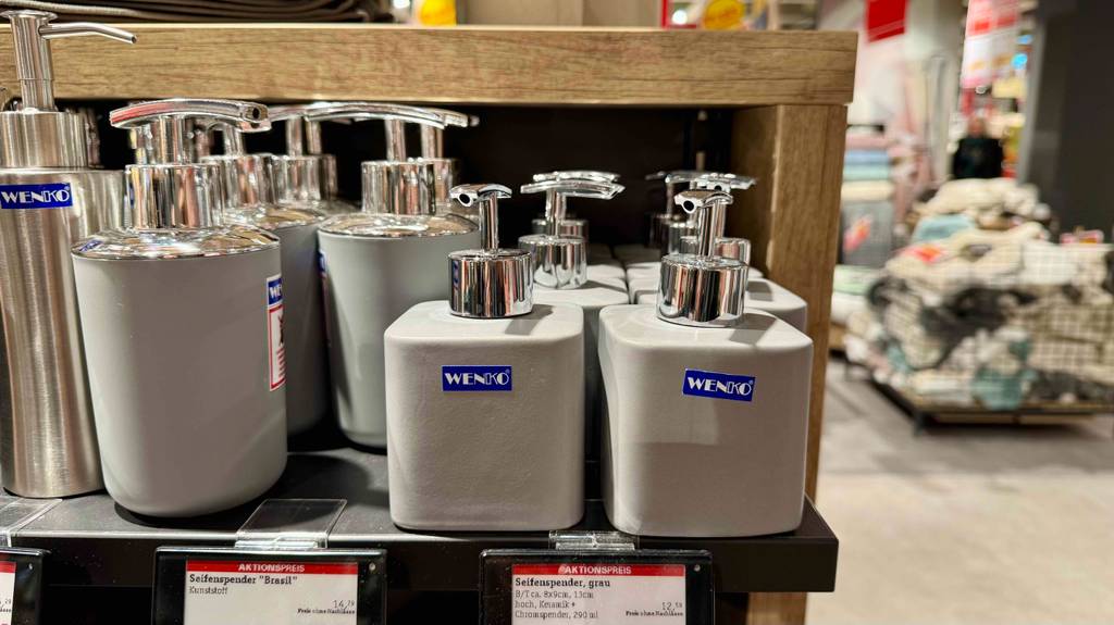 Seifenspender in grau im Test: Mehrere Spender stehen neben anderen Produkten in einem Regal.